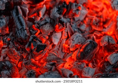 Background of burning and glowing hot coals.Flicker of burning coals at night.The texture of flaming burning firewood.Smoldering embers of fire. 