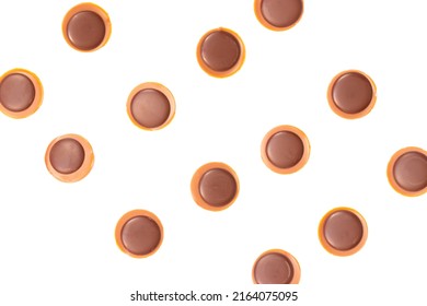 Background with caramel and chocolate sweets with hazelnut in it very similar to Toffifee in the lines next to each other separated on the white background.