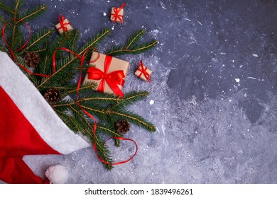 Background For A Christmas Card. Gifts And Fir Branches In A Santa Hat. Flat Lay, Copy Space