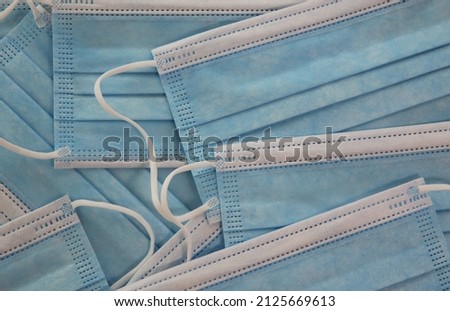Background of close up of multiple, light blue and white medical masks, protection against infectious disease