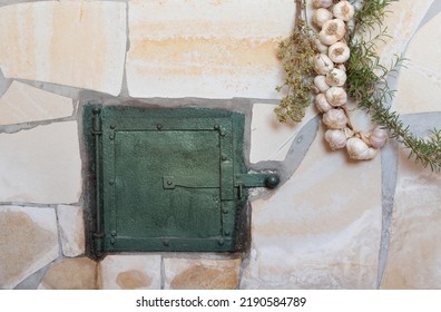 Background And Closeup Of A Traditional Oven With An Oven Door. Herbs And Garlic Hang Down On The Sides