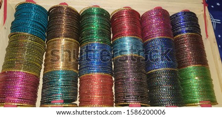 Background of colorful bangles stacked in a bangle box in India with glitter and plain colored bangles. The bangles are made of glass, metal or lac and worn regularly or on special occasions