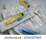 Background of colorful packaged plastic disposable syringes. Sterilized syringes in a package. Medical devices for administering drugs intravenously.