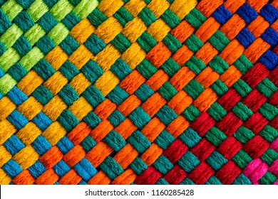 Background completely covered by diagonally angled rainbow colored interweaving threads of stitched fabric