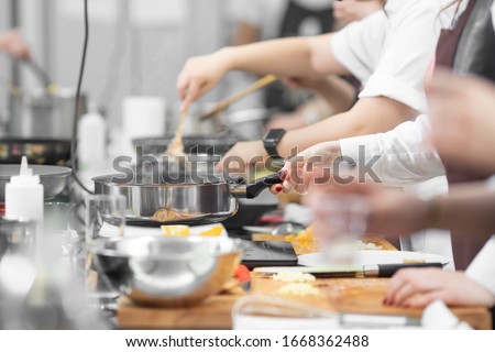 Background cook leads master class in cooking in kitchen.