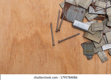 Background With Copy Space. Top View Of Four Nail And Group Of Nail Strip (for Nail Gun / Staple Gun) On Wooden Board For Carpentry And Woodworking Projects. Many Sizes Of Nails. Some Nail Are Rusted.