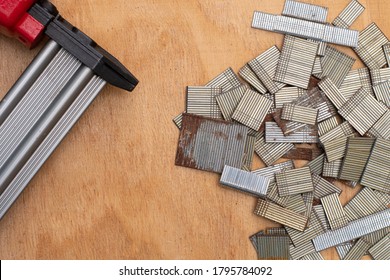 Background With Copy Space. Top View Of Nail Gun (Staple Gun) And Group Of Nail Strip On Wooden Board For Carpentry And Woodworking Projects. There Are Many Sizes Of Nails. Some Strip Are Rusted.