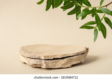 Background for cosmetic products of natural beige color. Stone podium with green leaves. Front view. - Shutterstock ID 1819084712
