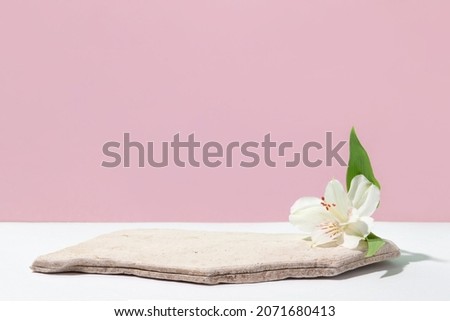 Background for cosmetic products of natural pink color. Stone podium with white flowers. Front view.