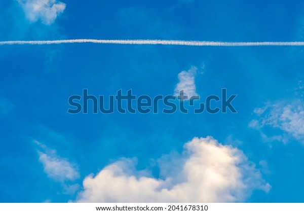 Background for the cover or\
slide of a presentation on the topic of air transportation and\
tourism. The blue sky is divided into two parts by the trace of the\
plane.