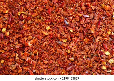 Background of crushed red cayenne pepper, dried chili flakes and seeds, top view. Ground red chili pepper, texture, background. Pile of crushed red peppers, background, top view.