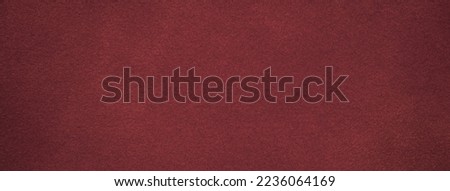 Background of dark red suede fabric closeup. Velvet matt texture of wine nubuck textile with gradient. Marron felt backdrop, vignette.