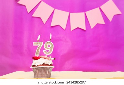 Background date of birth with number  79. Pink background with a cake and burning candles, save space, happy birthday anniversary for a girl. Holiday pudding muffin.