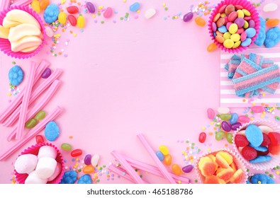 Background With Decorated Borders Of Bright Colorful Candy On Pink Wood Table For Halloween Trick Of Treat Or Childrens Birthday Party Favors.