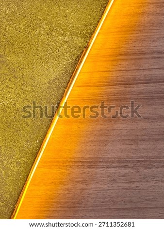 Background of a diagonal geometric pattern with two distinct textures for decoration. Interior decor combines handcrafted gold glitter and walnut wood separated by a diagonal strip of yellow lighting.