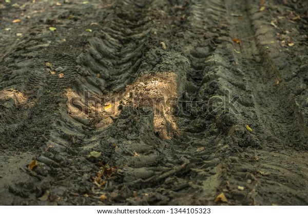 Background dirty slippery tracks of\
automobile tires in clay. Road wheel on land all\
terrain