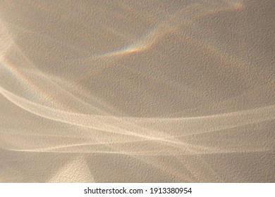 Background with the effect of reflection of abstract shiny lines with natural shadows and rays of light from a window on a textured wall in a delicate sandy color. Copyspace for mockup and posters.