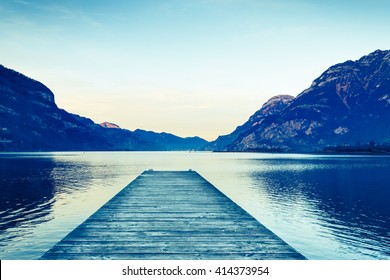 Background As Epic Mountain Landscape.  Lake At Sunset  With Wooden Pier. Bleach Bypass Effect.