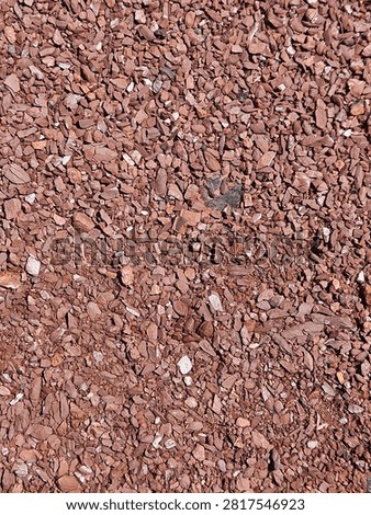 A background filled with small brown and red crushed stones. Rough gravel texture, suitable for architectural concepts, landscaping projects, and industrial design visuals. 