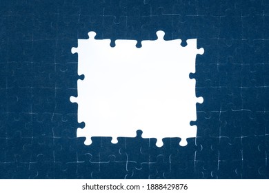 background of folded puzzle pieces with an empty space in the center, white window framed by a puzzle