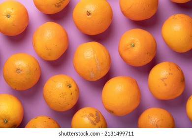 Background of fresh and healthy oranges, seasonal and irregular, ugly and flawed, on violet background, forming a repetitive texture or pattern