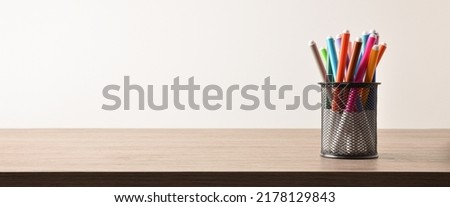Background with group of markers of various colors in a pencil on a wooden table and white isolated background. Front view. Horizontal panoramic composition.