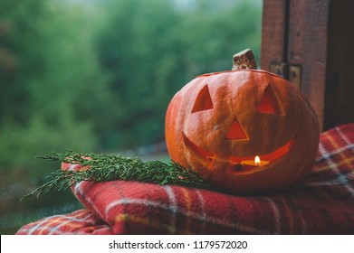 Background Halloween Pumpkin On A Cozy Window Sill With A Red Plaid. Whole Pumpkin And Sparkler Outdoors. Happy Halloween! Autumn Is Cozy. Rain Outside.