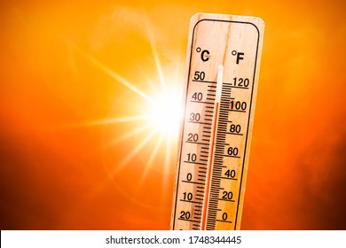 Background for a hot summer or heat wave, orange sky with with bright sun and thermometer