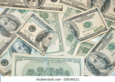 A background of hundred dollar bills with one torn in half on top