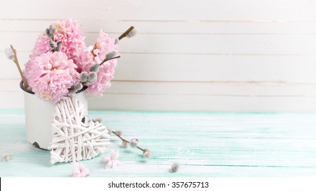 Background  with hyacinths,  willow flowers  in aged mug and decorative heart  on turquoise painted wooden planks against white wall. Selective focus and empty place  for your text. Toned image.