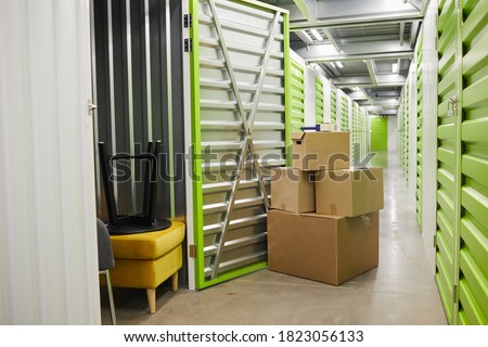 Background image of cardboard boxes stacked by open door of self storage unit, copy space