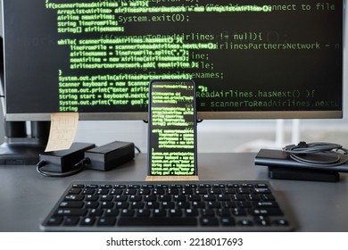Background image of computer screen with green code lines, focus on smartphone in foreground, copy space