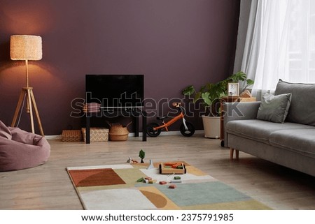 Background image of cozy living room interior with maroon wall and childrens toys scattered on carpet, copy space