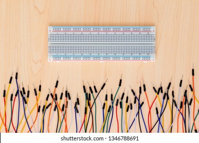 Background image of electronic wires and a breadboard. Wires on a timber background with an electronics breadboard. Hobby electronic wires with pins at the end.