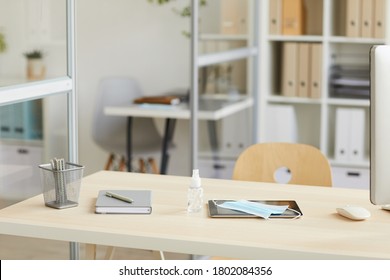 Background Image Of Empty Workplace Desk With Face Mask And Hand Sanitizer In Post Pandemic Office, Copy Space