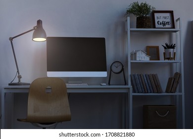 Background Image Of Home Office Workplace At Night, With Focus On Computer Desk Lit By Dim Lamp Light, Copy Space