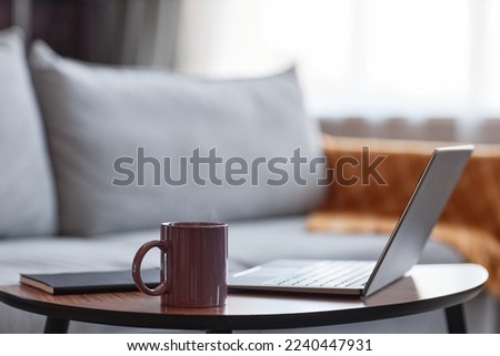 Background image of mauve coffee mug next to open laptop in cozy home setting, copy space