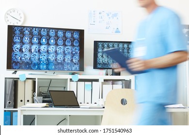 Background Image Of Modern Computer Equipment With CT Brain Scans On Screens At Work Station And Blurred Shape Of Unrecognizable Medic Walking In Foreground, Copy Space
