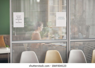 Background Image Of Office Room With Sign Interview In Progress On Glass Wall And Silhouettes Of People, Copy Space