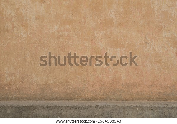 Background\
image of an old painted scratched wall of light brown pink color\
with a smooth horizontal gray concrete \
ledge.