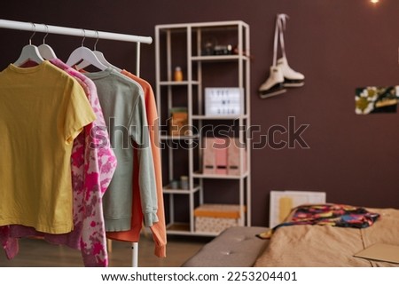 Background image of open closet and clothes on hangers in teenage girls room, copy space