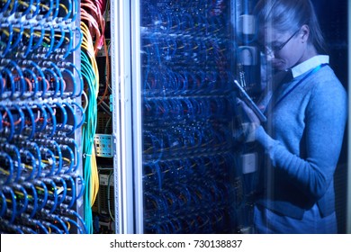 Background image of supercomputer server cabinets with wires in research center with reflection of female engineer in dark glass