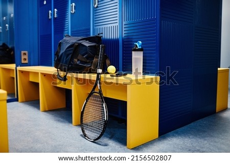 Background image of tennis racket and sports equipment in locker room in vibrant blue color, copy space