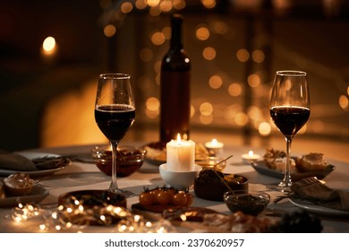 Background image of two wine glasses on dinner table with Christmas lights and candles, copy space