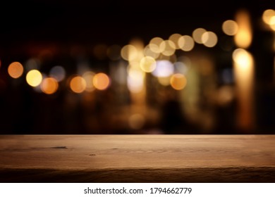 background Image of wooden table in front of abstract blurred restaurant lights