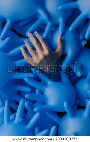 background of inflated blue medical latex gloves, in the center is a woman's hand in a transparent glove