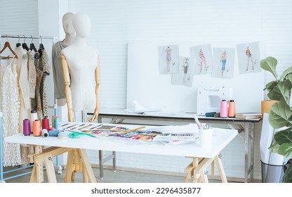 Background of interior tailor shop or room with nobody, there are mannequin, clothes, thread, sewing machine on table and paper of clothing design on wall. Lifestyle and small business concept - Powered by Shutterstock