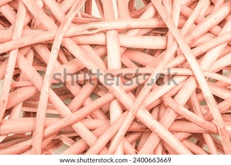Background of intersecting intertwined lines of rustic ratana vine sticks in the color of the year 2024 peach fuzz, pantone. Ratan woven mesh. Ratan weaving.Pantone 2024