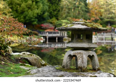 Background with japanese traditional old stone lantern near the lake in the Japanese garden.  Japanese lantern with moss in Japanese garden, Seattle. 