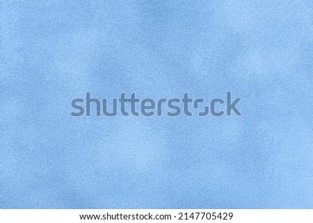 Background of light blue suede matte fabric closeup. Velvet matt texture of sky nubuck textile. Velveteen pattern. Structure of denim cloth, macro